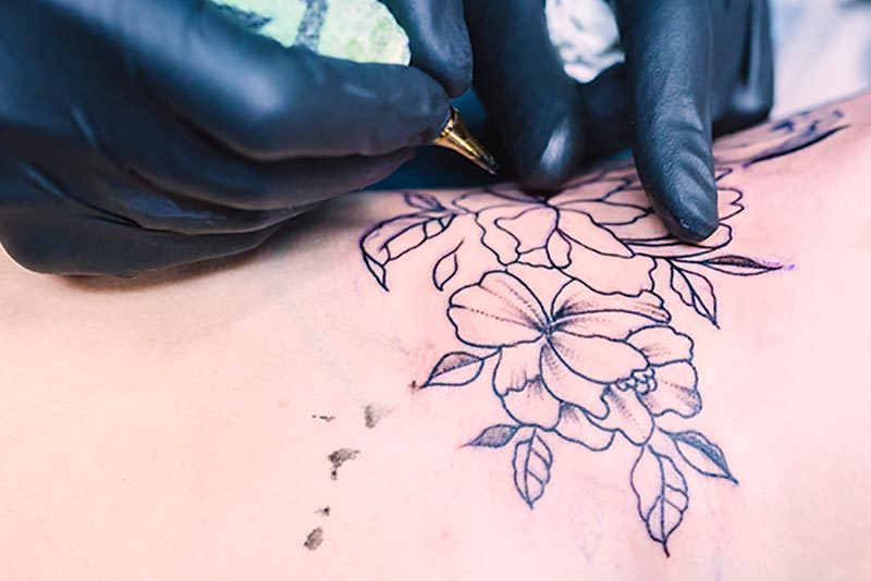 hands-making-flower-tattoo-with-needle