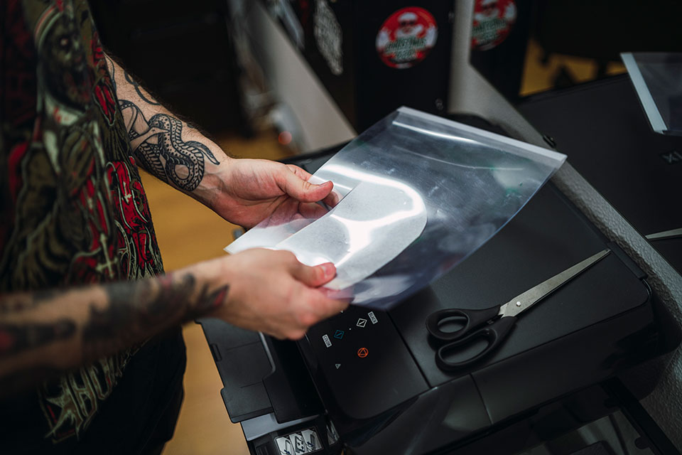 thermal_printer tattoo artist using tattoo stencil transfer paper in a tattoo shop