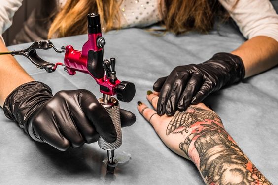 women-tattoo-artist-tattooing-hand