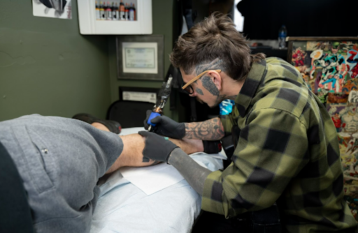 artist working in a tattoo parlor artist working in a tattoo parlor