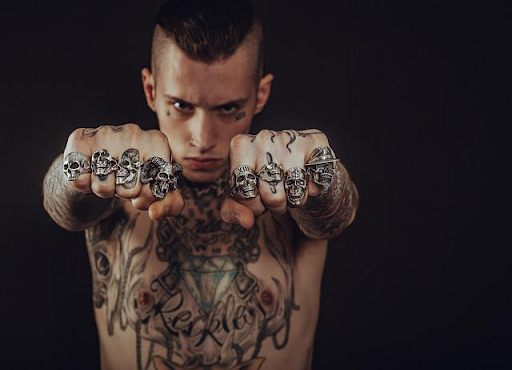 man with tattoo and skull rings