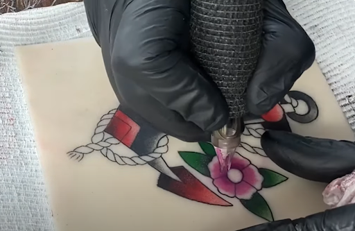 tattoo artist using tattoo machine on practice skin tattoo artist using tattoo machine on practice skin